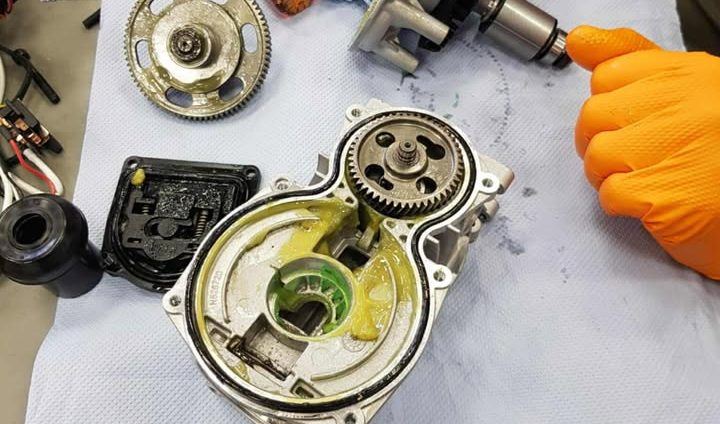 Componente de motor dezasamblate cu mâna unei persoane ținând o piesă, prezentând elementele interne.